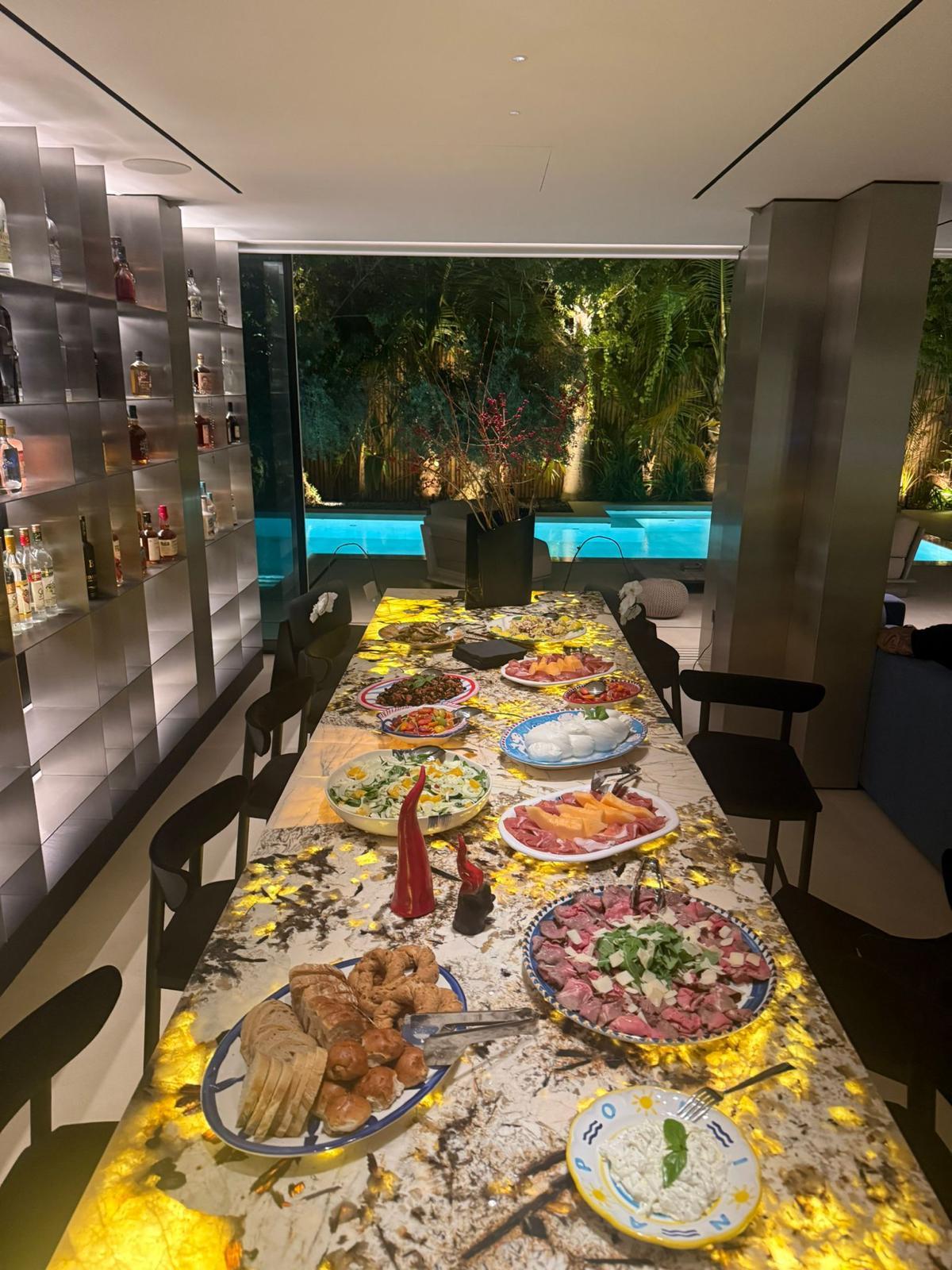 A long table laid with antipasti beside a lit pool in a private Dubai home