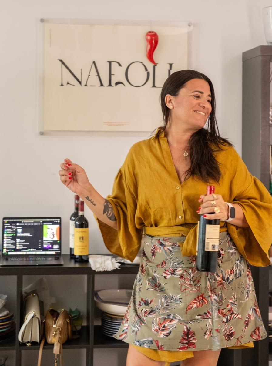 Giordana with the wine, under the Napoli poster and its cornicello