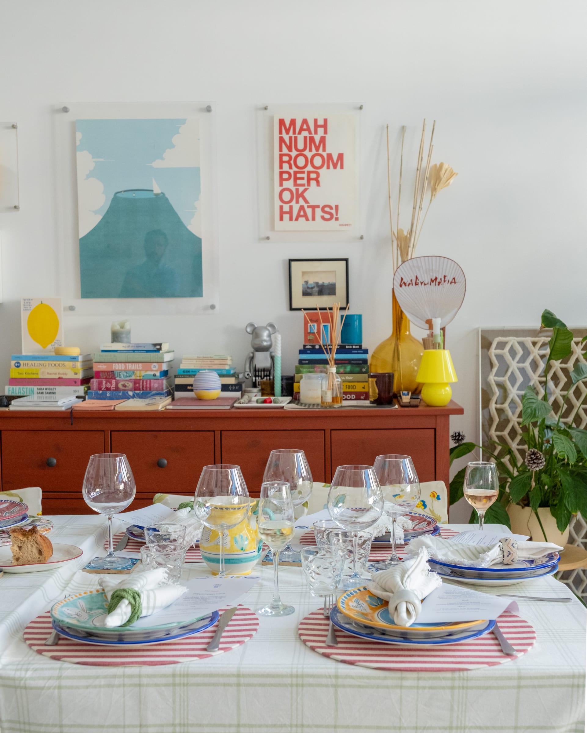 A table laid for a supper: striped placemats, hand-painted plates, wine glasses and a menu at every seat