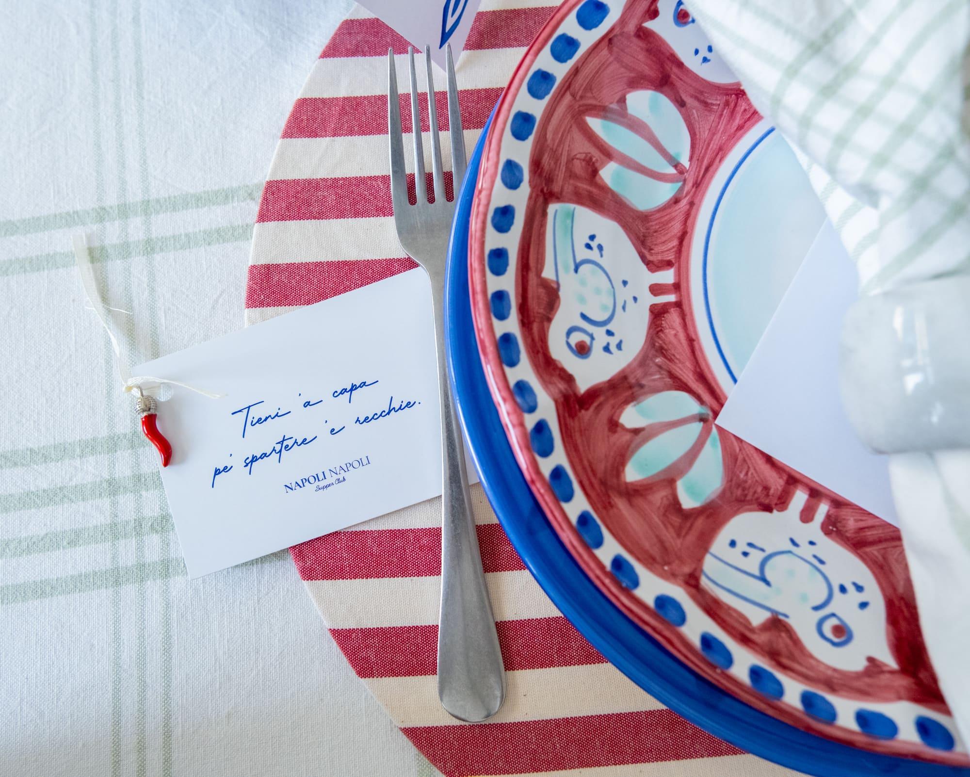 A hand-painted red-and-blue Vietri plate with a Napoli Napoli place card